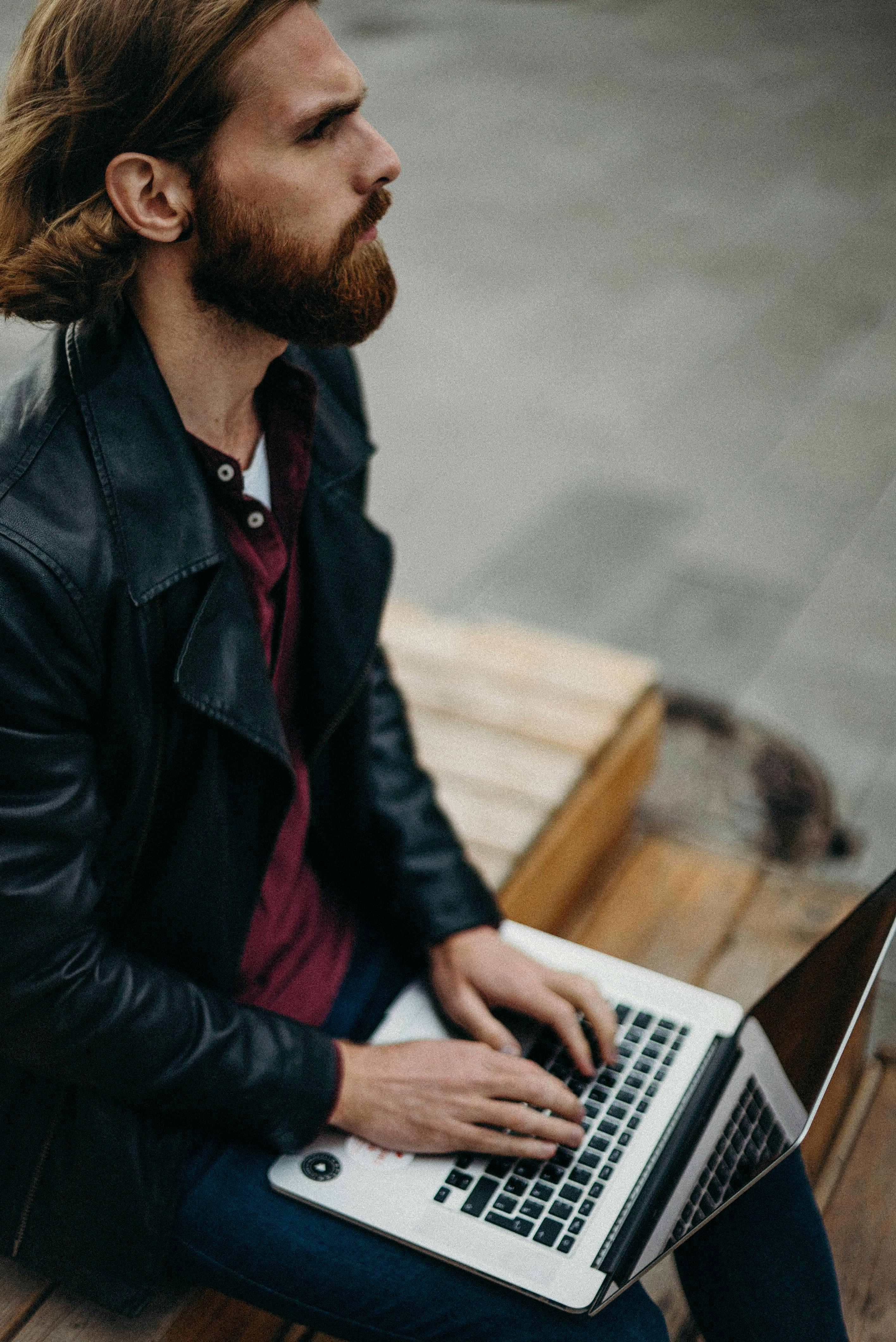 A freelance developer typing on a laptop while sitting outdoors