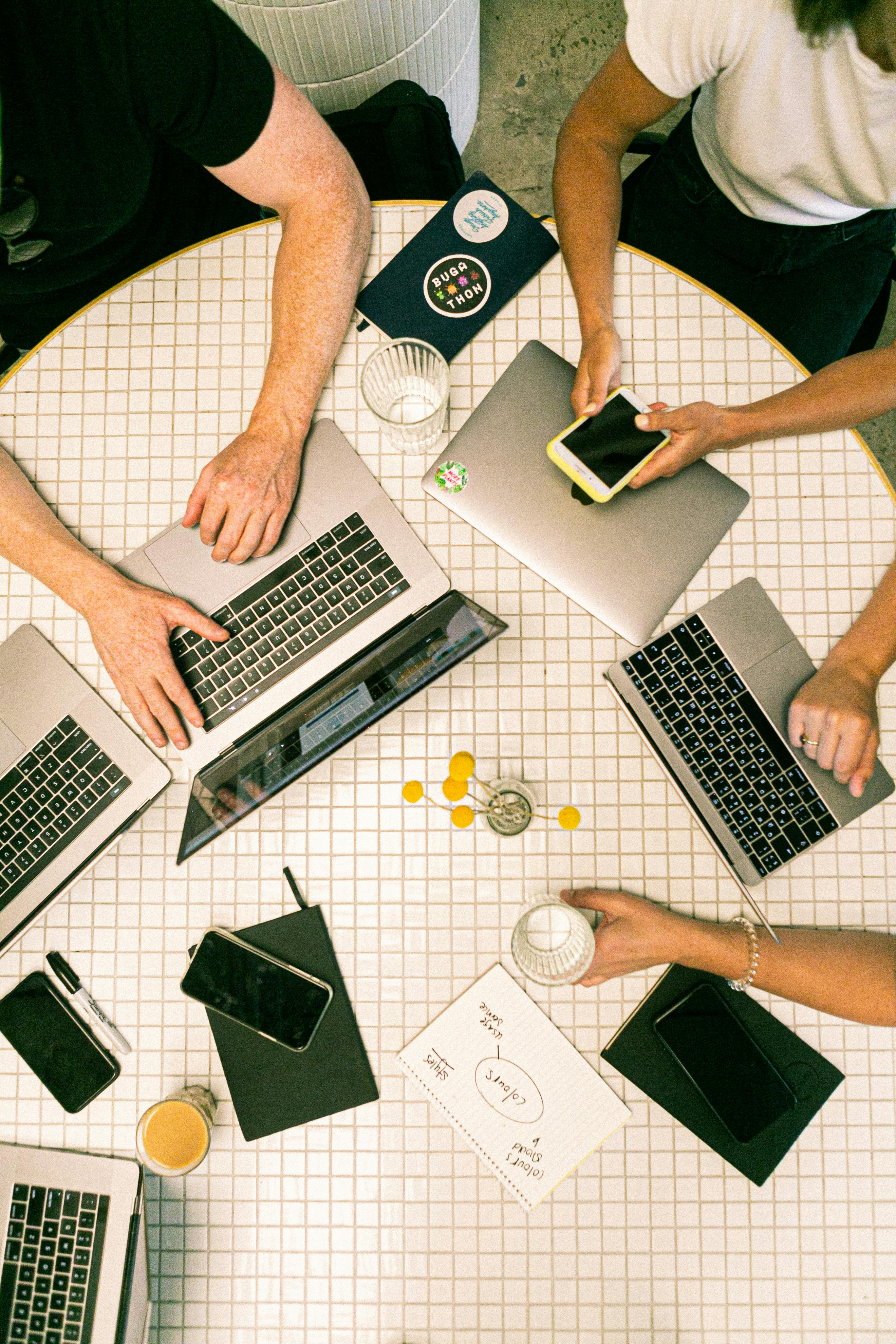 A team working together around a table covered in laptops, phones and notebooks